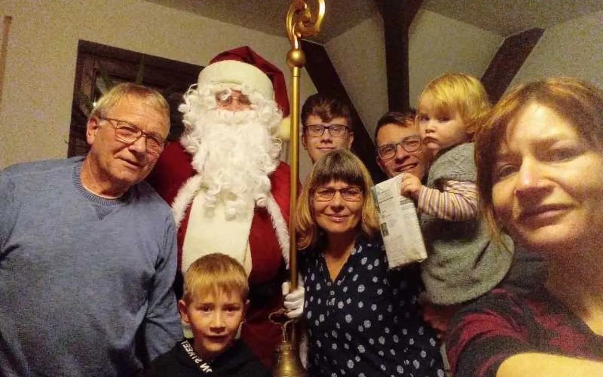 Weihnachtsmann bei einer Familienfeier mit mehreren Generationen Familie mit Oma, Opa, Mama, Papa und Kindern steht gemeinsam mit dem Weihnachtsmann