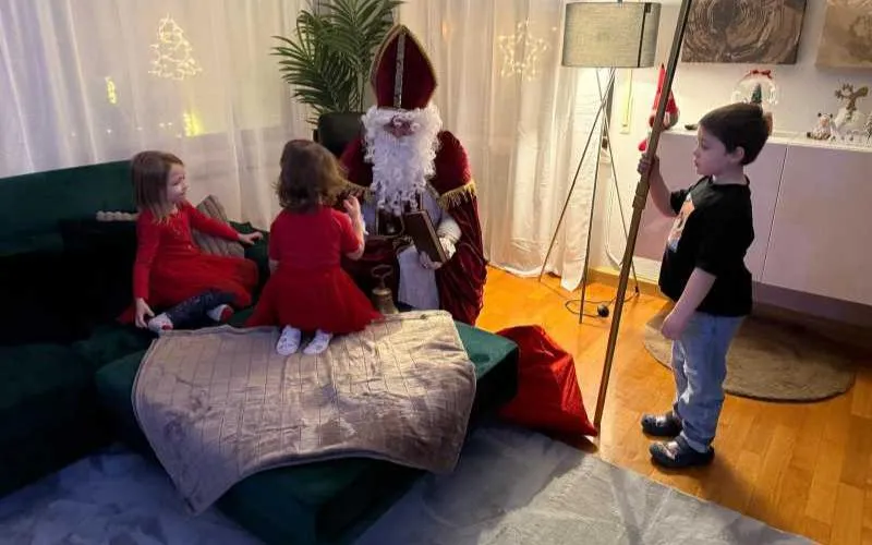 Nikolaus im Gespräch mit Kindern Ein Junge hält den Bischofsstab, während zwei kleine Mädchen mit dem Nikolaus reden